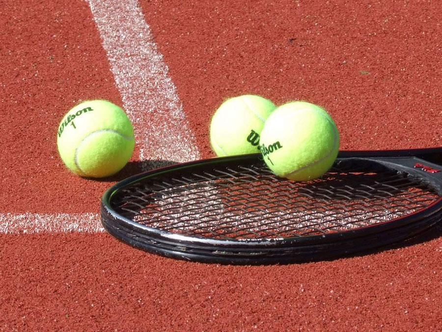 Hotel Sägerhof in Tannheim – Tennisschläger und Bälle auf dem Tennisplatz | Wellnesshotel Tannheimer Tal