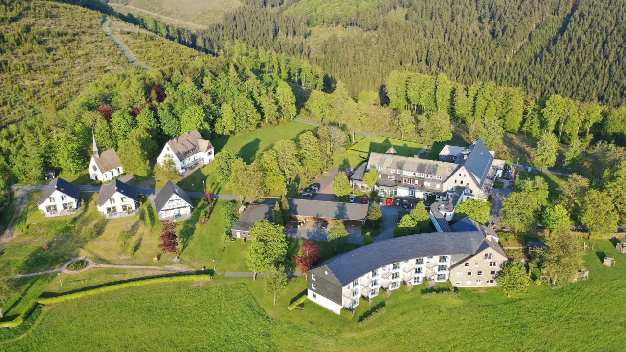 Luftaufnahme des Berghotels Hoher Knochen, eingebettet in grüne Wiesen und dichte Wälder des Sauerlands.