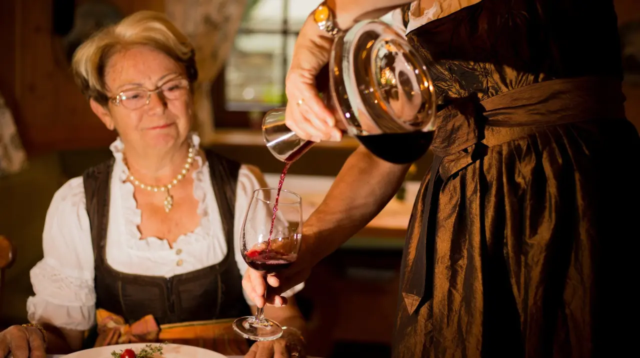 Gast wird Wein im traditionellen Restaurant des Appart- und Wellnesshotel Charlotte Seefeld serviert.