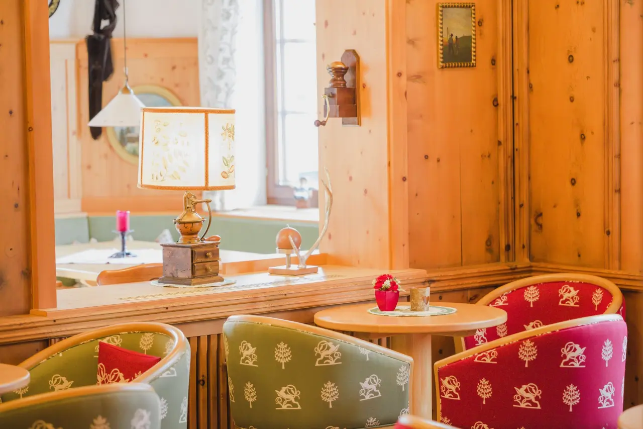 Traditioneller Sitzbereich mit Holzwänden, gemusterten Stühlen und Tischlampe im Appart- und Wellnesshotel Charlotte Seefeld.