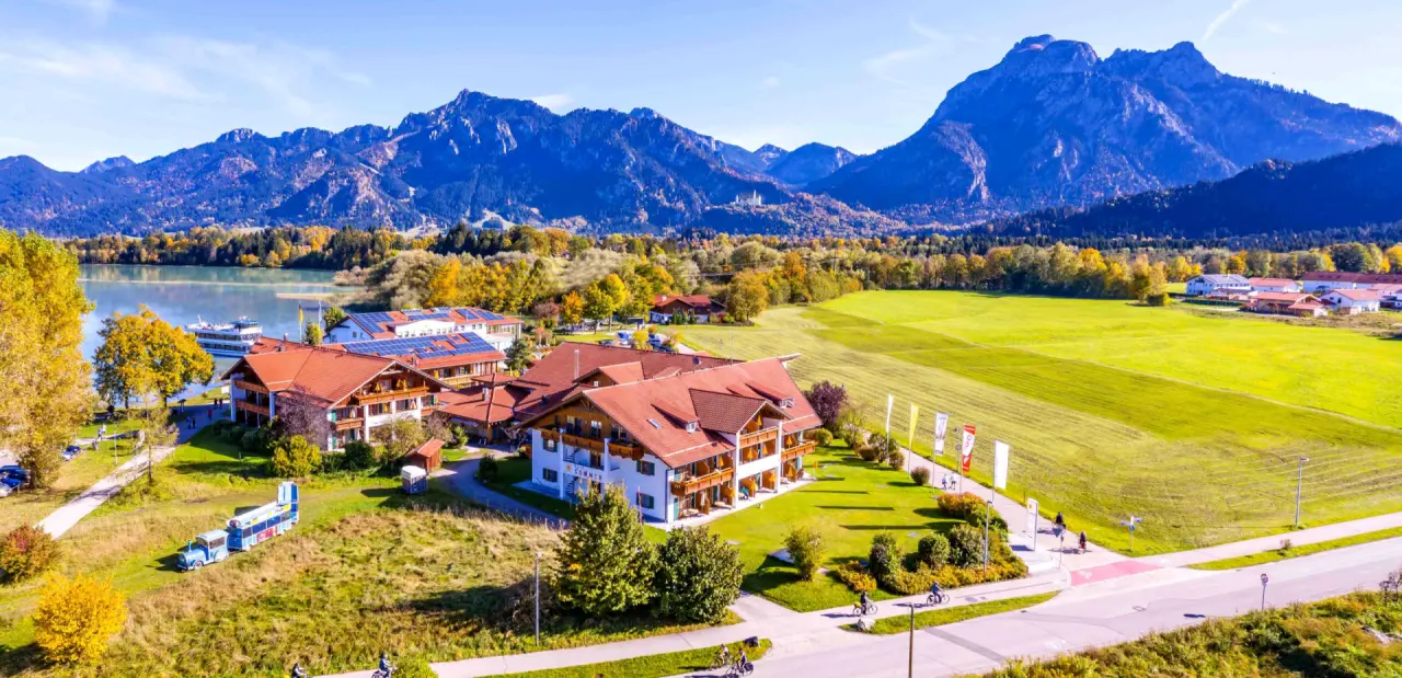 Panorama-Aussenansicht des Hotel Sommer am See mit herbstlicher Landschaft und Alpenpanorama im Hintergrund.