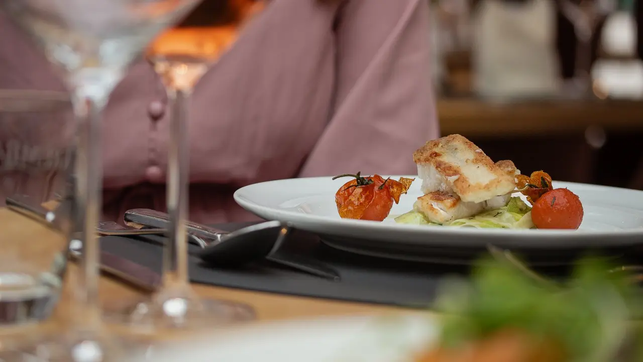 Gebratenes Fischfilet mit Kirschtomaten und Salat auf einem Teller im Restaurant des Hotel Sommer.