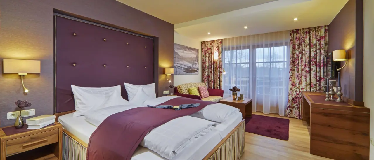 Komfortables Doppelzimmer im Hotel Sommer mit gemütlichem Bett, Sitzbereich und Balkonblick.