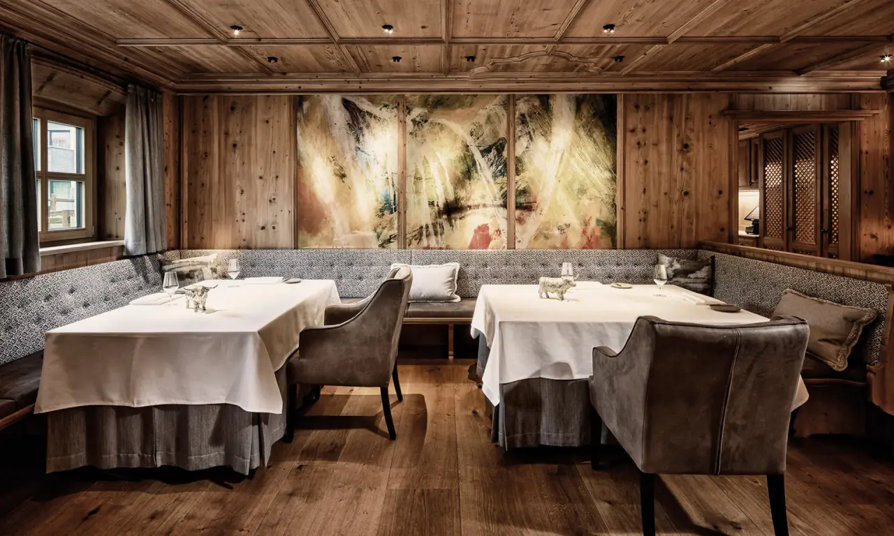 Elegantes Restaurant im alpinen Stil mit Holzwänden, bequemen Sitzbänken und Kunstwerken im Burg Vital Resort.