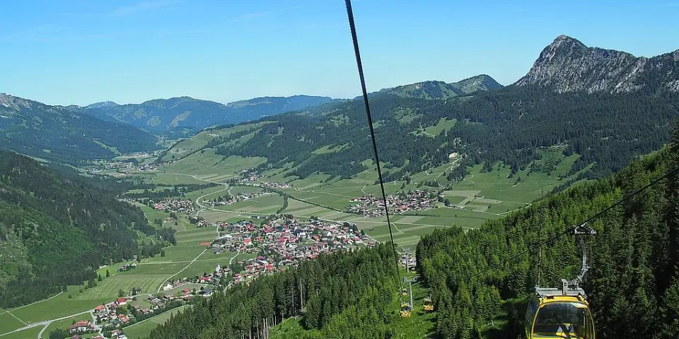 Malerischer Panoramablick auf das Tal und die Alpenlandschaft vom Hotel Bergblick, mit Seilbahn und grünen Wäldern.
