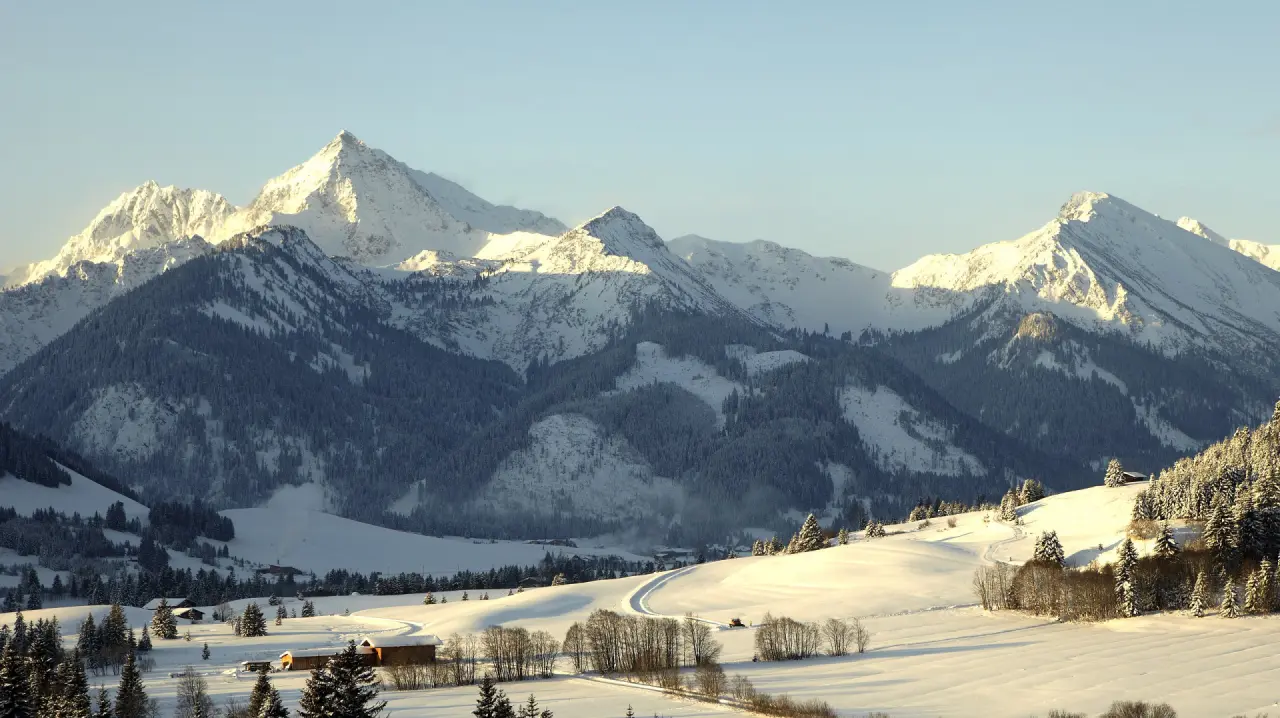 Majestätisches Winterpanorama mit verschneiten Alpen und Tannenwäldern, sonnenbeschienene Gipfel im Hotel Bergblick.