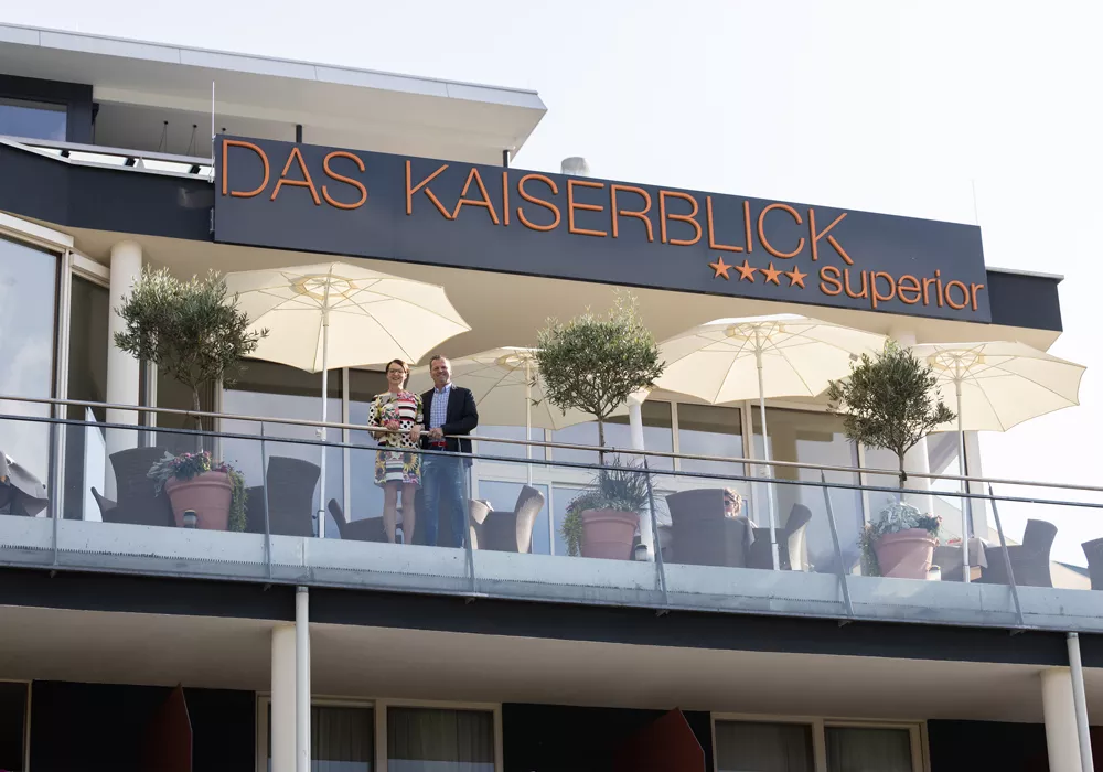 Hotel Kaiserblick in Ellmau – Außenansicht des Hotels mit Logo und Sonnenterrasse | Wellnesshotel Tirol
