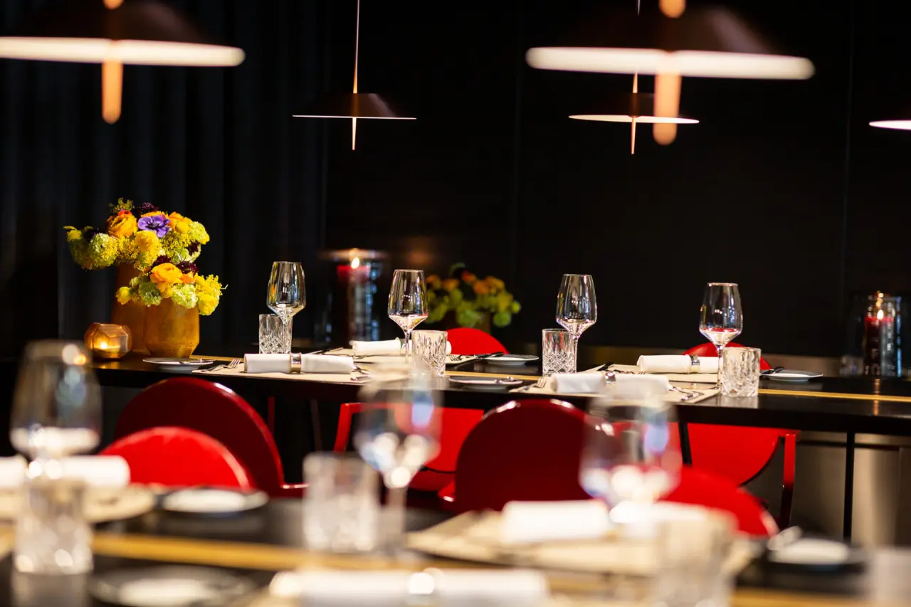 Elegant gedeckte Tische im Restaurant des Interalpen-Hotel Tyrol mit roten Stühlen und Blumenarrangements.