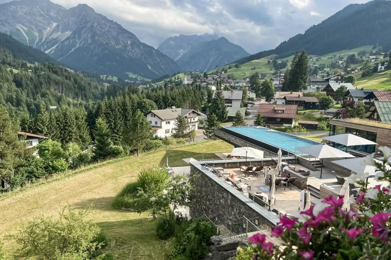 Infinity Pool mit Bergblick im Travel Charme Ifen Hotel. Entspannung auf der Sonnenterrasse in den Alpen.