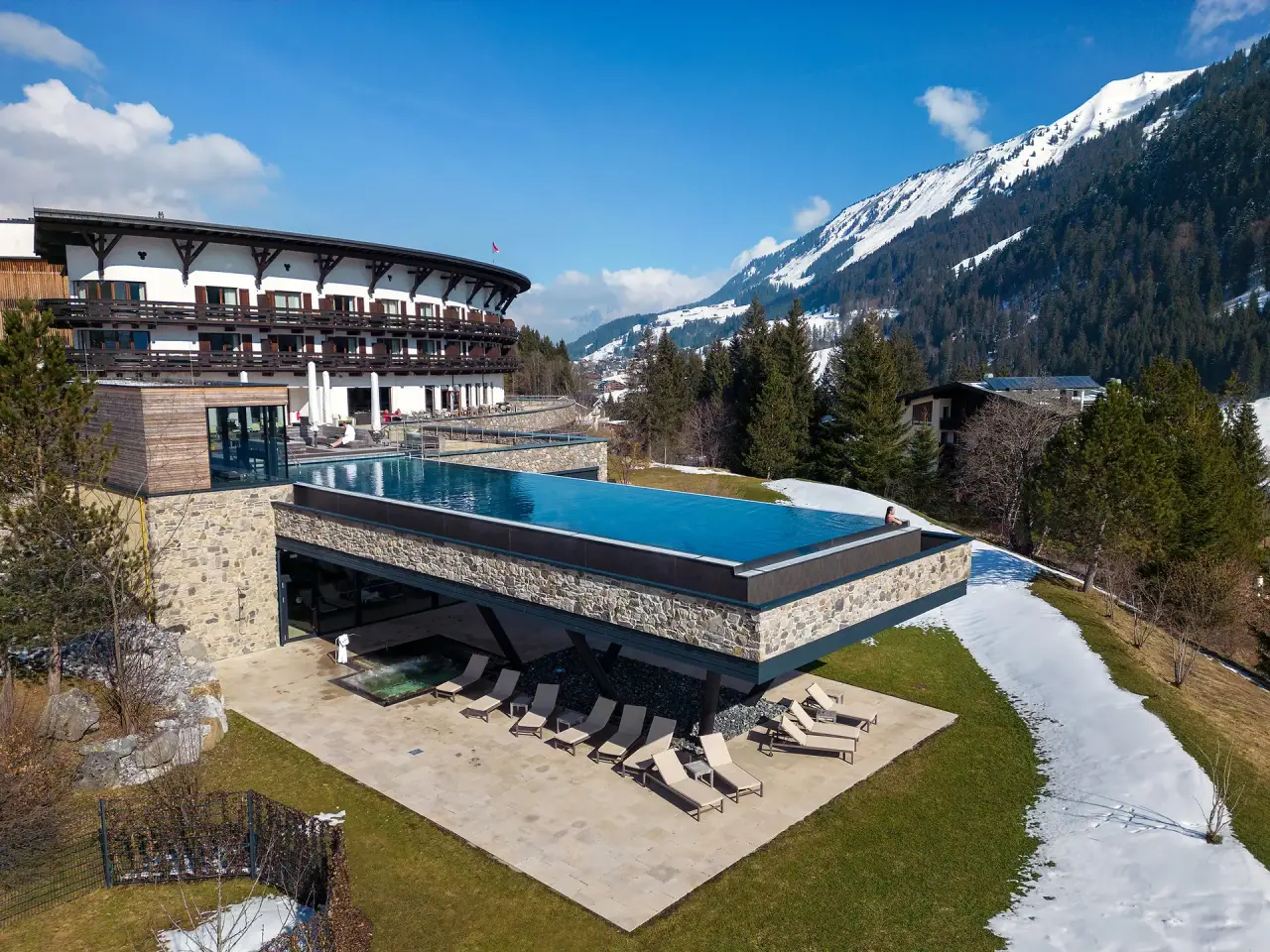 Infinity Pool mit Bergblick und Hotel Travel Charme Ifen Hotel im Kleinwalsertal. Luxuriöser Wellnessbereich mit Alpenpanorama.