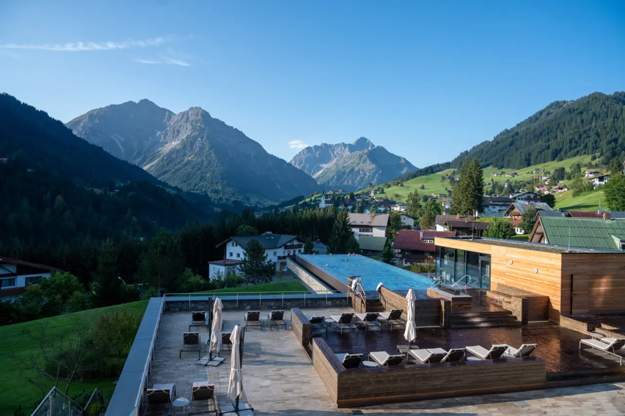 Aussen-Infinitypool mit atemberaubendem Bergpanorama und Sonnenterrasse im Travel Charme Ifen Hotel.