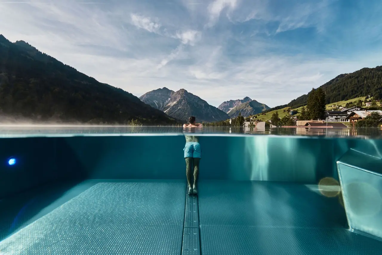Spektakulärer Infinity Pool mit Bergpanorama und Unterwasseransicht im Travel Charme Ifen Hotel. Entspannung pur in den Alpen.