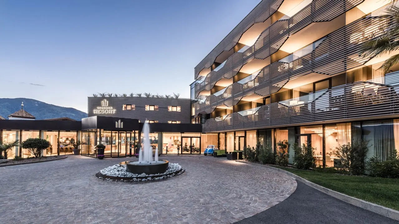 Schenna Resort in Schenna – Moderne Außenansicht bei Dämmerung mit Brunnen | Wellnesshotel Südtirol