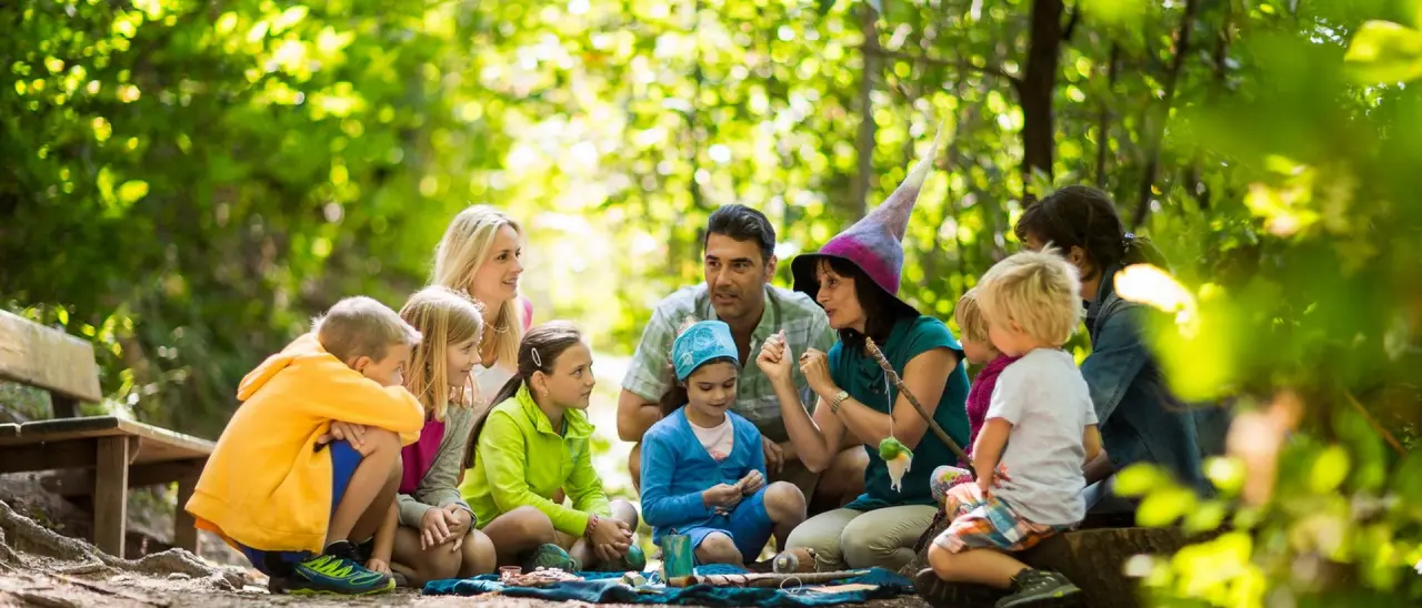Schenna Resort in Schenna – Kinder und Erwachsene bei einer Märchenstunde im Wald | Wellnesshotel Südtirol