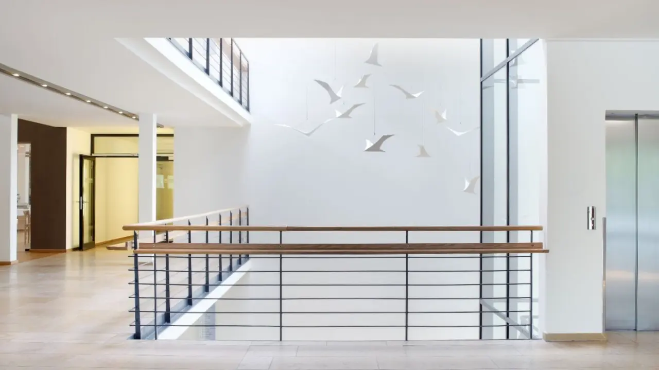 Modernes Treppenhaus und Aufzugsbereich mit schwebenden Vogel-Dekorationen im Ostseehotel Dierhagen.