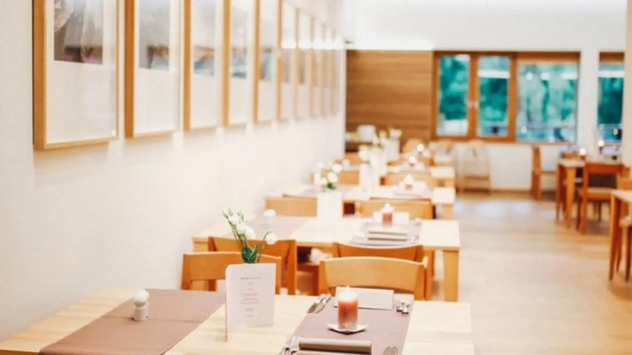 Heller, modern eingerichteter Restaurantbereich mit Holztischen und Blick ins Grüne im Ostseehotel Dierhagen.