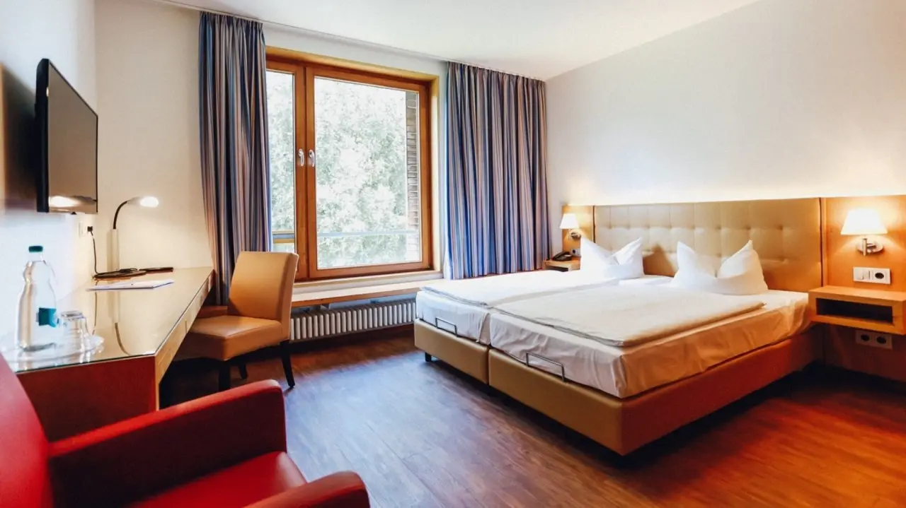 Helles Doppelzimmer im Ostseehotel Dierhagen mit bequemen Betten, Schreibtisch und Blick ins Grüne.
