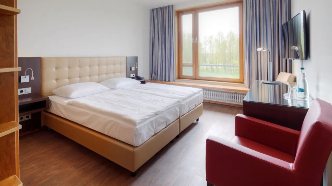 Helles Doppelzimmer im Ostseehotel Dierhagen mit bequemen Betten, Schreibtisch und Blick ins Grüne.