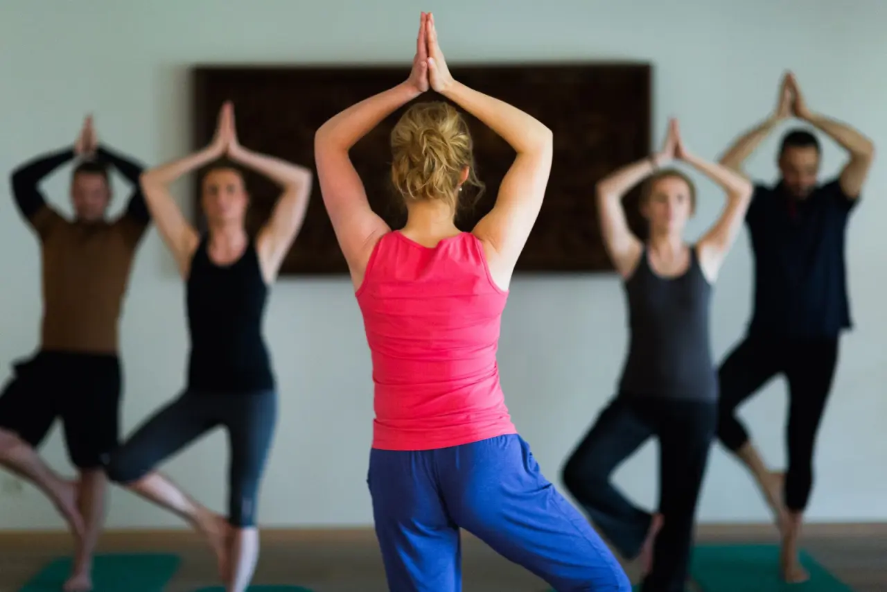 Yoga-Kurs mit Teilnehmern in der Baum-Pose im Fitnessbereich des Gut Klostermühle Alt Madlitz.