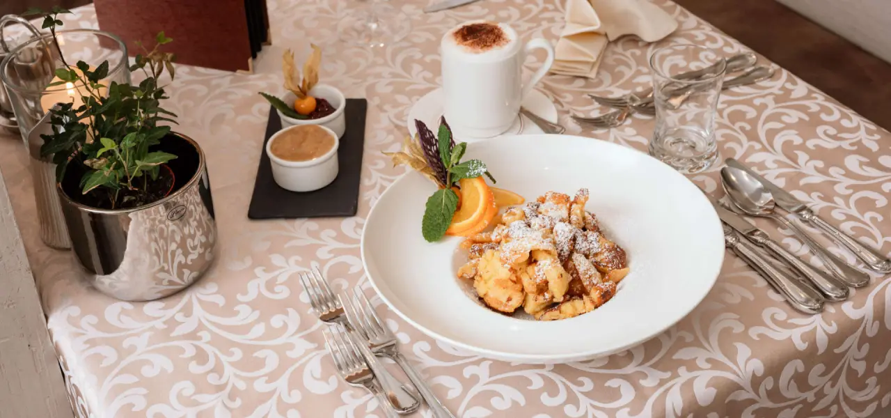 Kaiserschmarrn mit Apfelmus und Kaffee auf elegant gedecktem Tisch im Restaurant des Hotel Wastlhof.