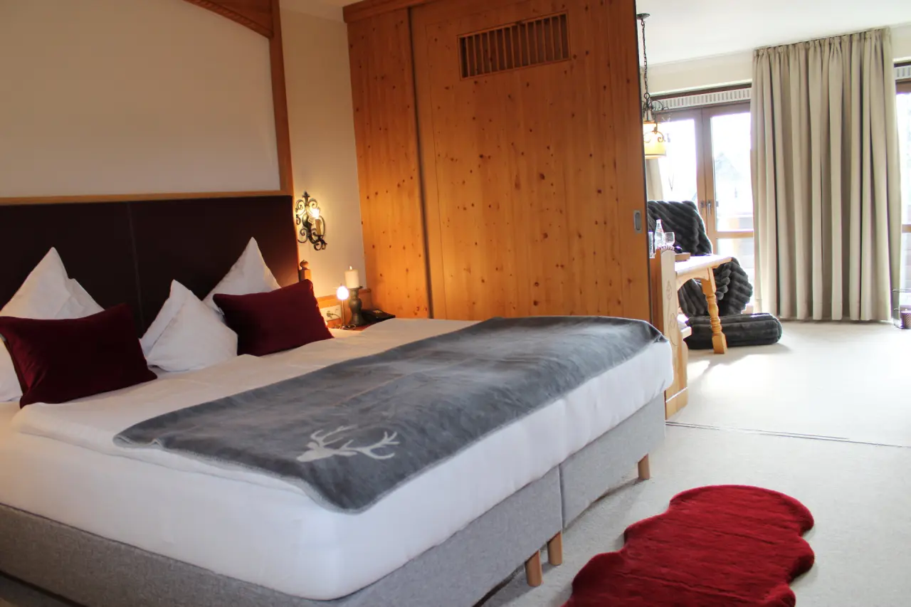 Gemütliches Doppelzimmer im alpinen Stil mit Holzelementen und Balkonzugang im Hotel & Residence Hochriegel.