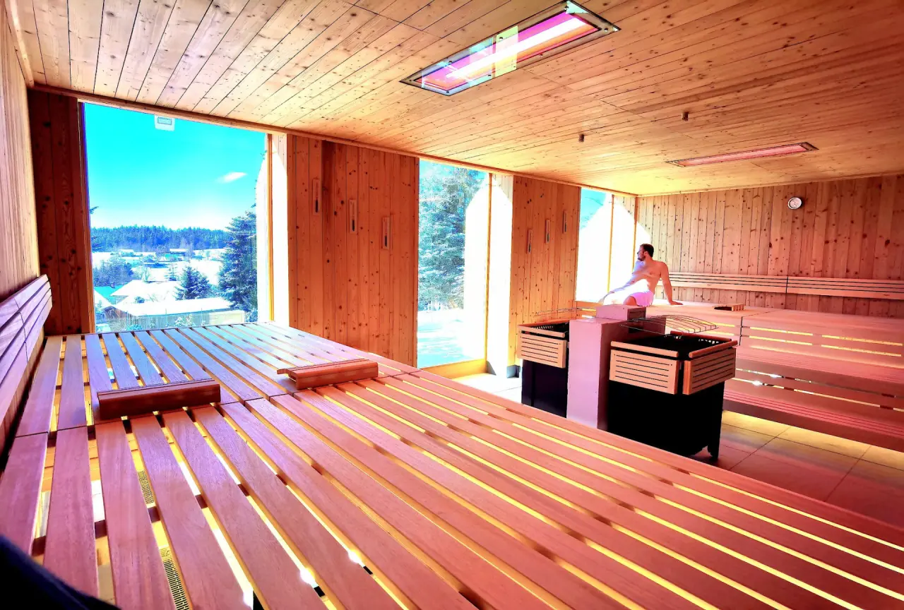 Panorama-Sauna im Hotel & Residence Hochriegel mit entspanntem Gast und weitem Blick auf die verschneite Winterlandschaft.