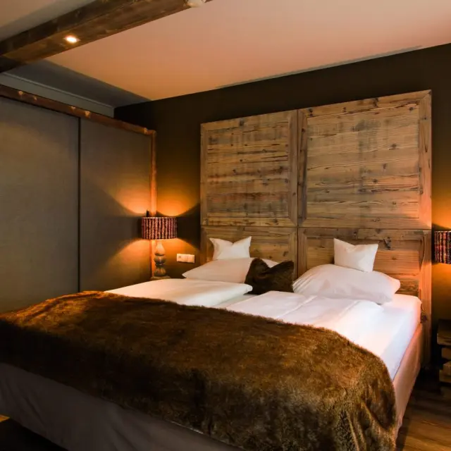 Gemütliches Doppelzimmer im alpinen Stil mit Holzkopfteil und warmem Licht im Stefanie Sport & Vital Hotel.