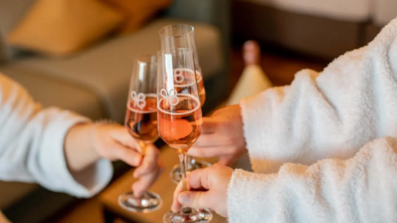 Gäste im Bademantel stoßen mit Rosé-Sekt an im Pfalzblick Wald Spa Resort. Entspannung und Genuss im Wellnessurlaub.
