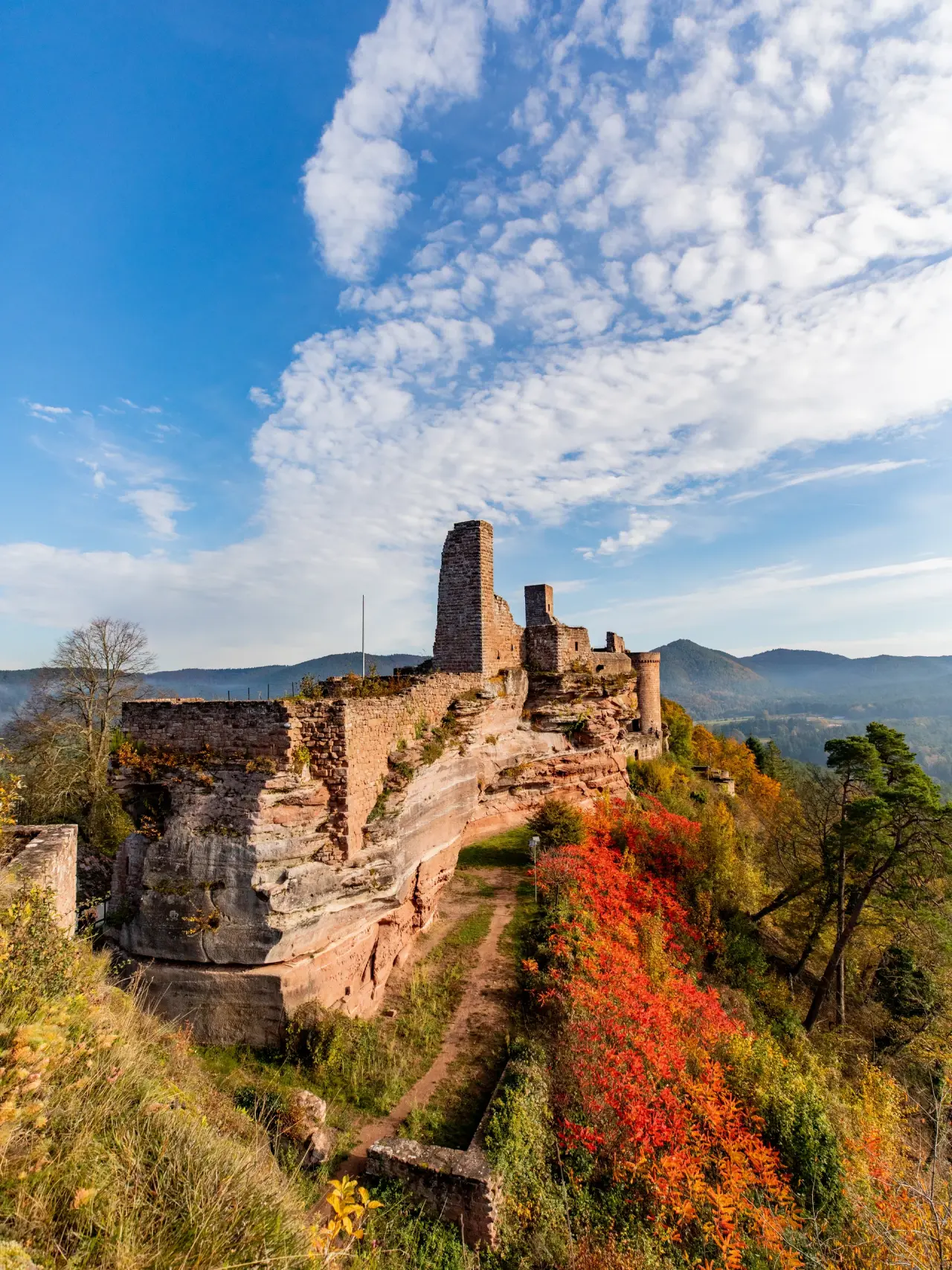 Herbstliche Landschaft mit Burgruine und farbenprächtigen Bäumen nahe dem Pfalzblick Wald Spa Resort.
