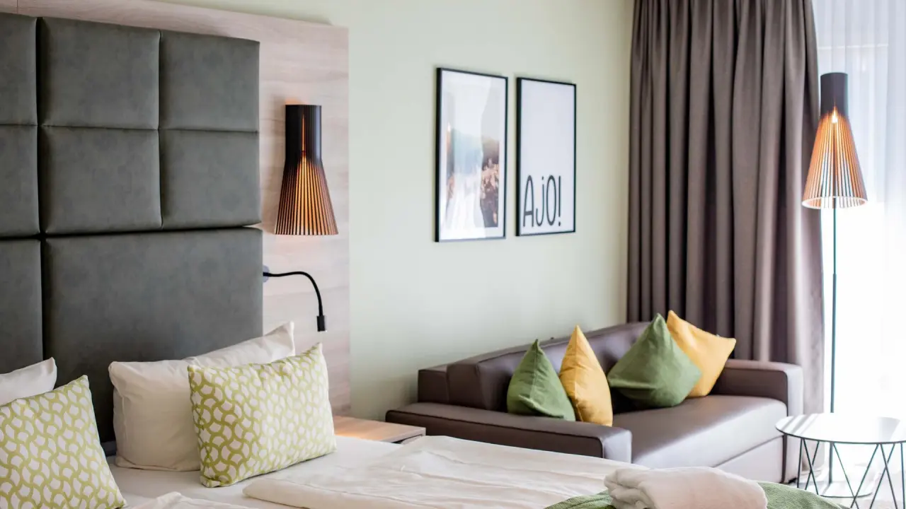 Modernes Doppelzimmer mit bequemen Bett, Sofa und stilvollen Lampen im Pfalzblick Wald Spa Resort.