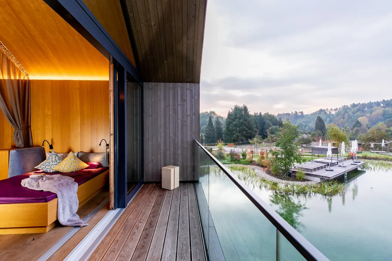 Gemütliches Hotelzimmer mit Balkon und Blick auf den Naturbadeteich im Pfalzblick Wald Spa Resort.