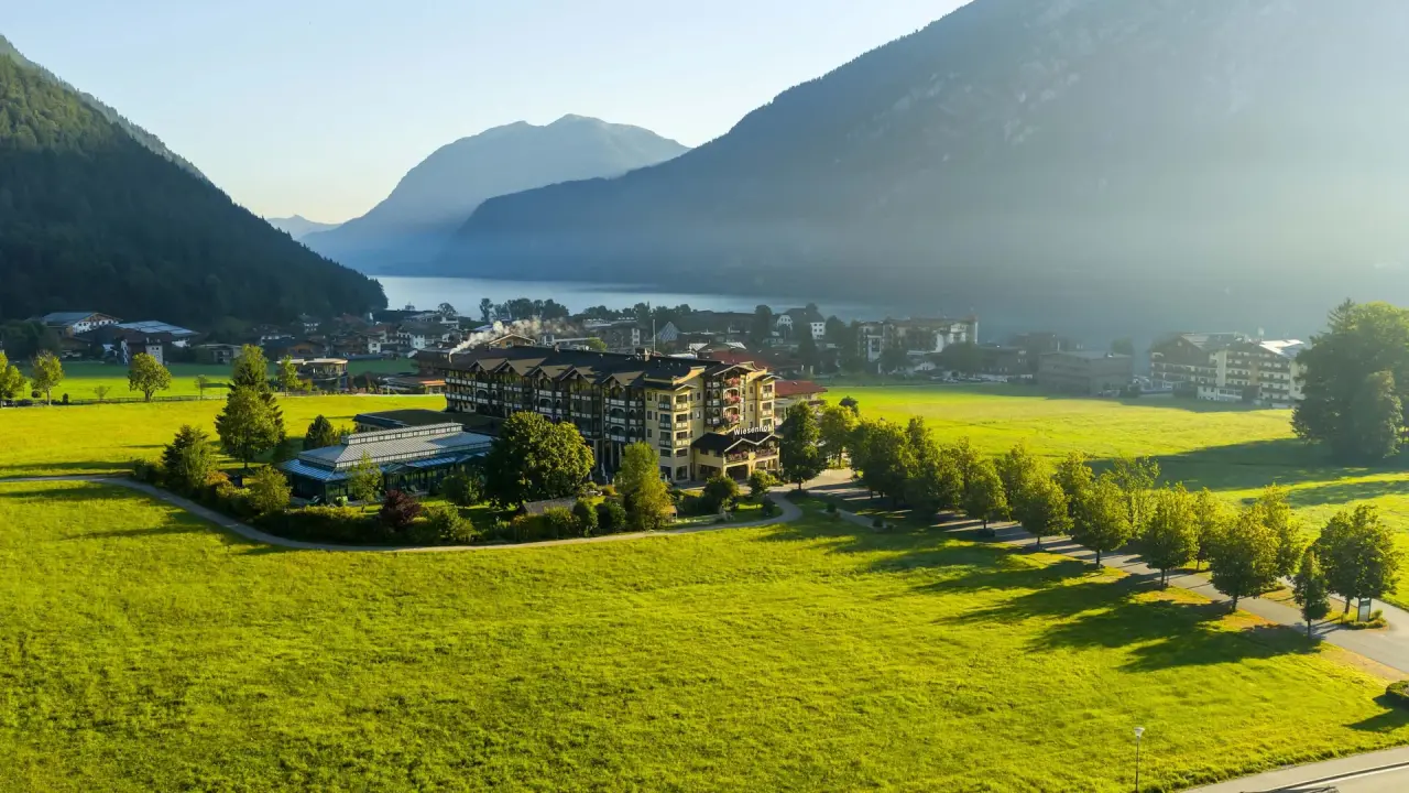 Panoramablick auf das Hotel der Wiesenhof am Achensee, umgeben von grünen Wiesen und majestätischen Bergen.