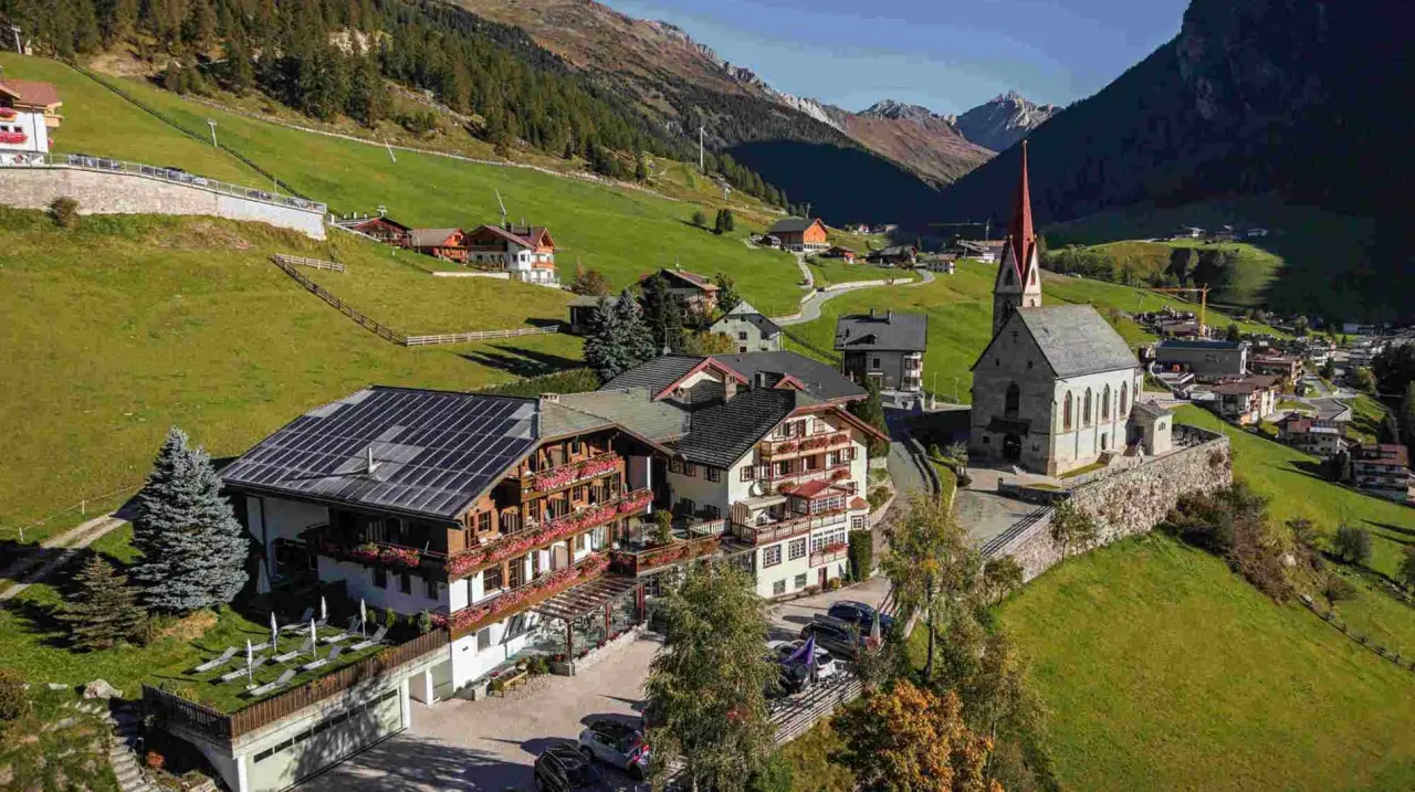 Hotel Berger in Rein in Taufers – Panorama-Außenansicht mit Bergkulisse und Kirche | Wellnesshotel Südtirol
