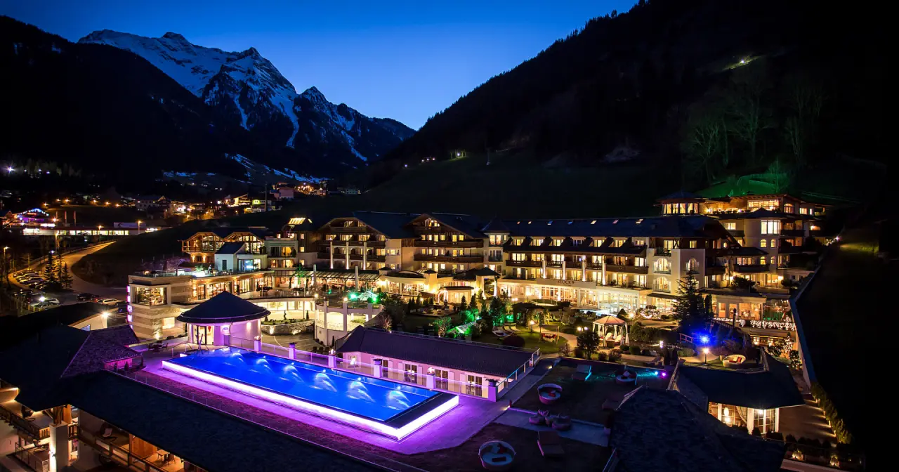 Nachtansicht des luxuriösen Stock Resort mit beleuchtetem Aussenpool und schneebedeckten Bergen im Zillertal.