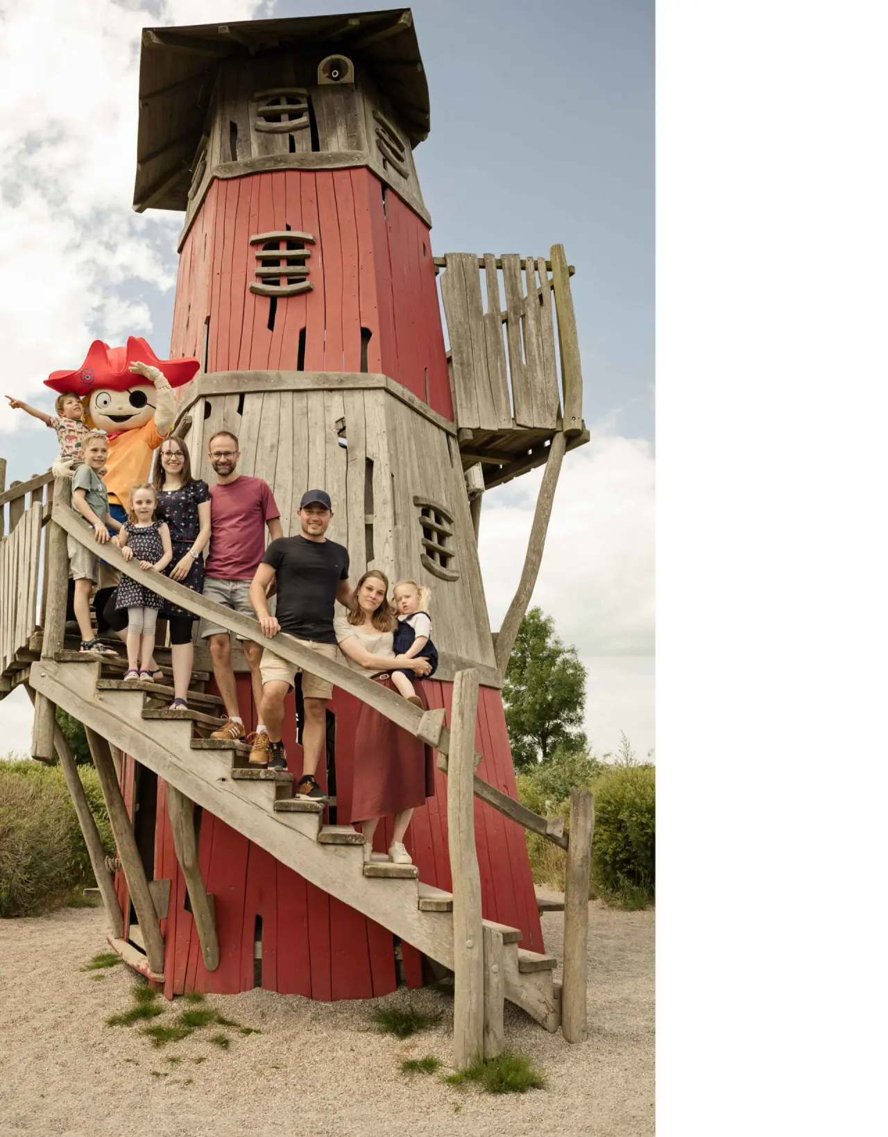 Familie mit Hotelmaskottchen auf einem roten Leuchtturm-Spielplatz im Familien Wellness Hotel Seeklause.