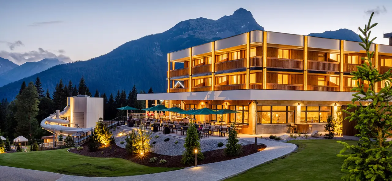 Beleuchtetes Zugspitz Resort bei Sonnenuntergang mit Restaurantterrasse und Alpenpanorama