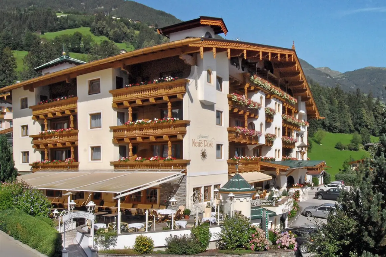Traditionelles Ferienhotel Neue Post in den Alpen mit blumengeschmückten Holzbalkonen und Bergblick.