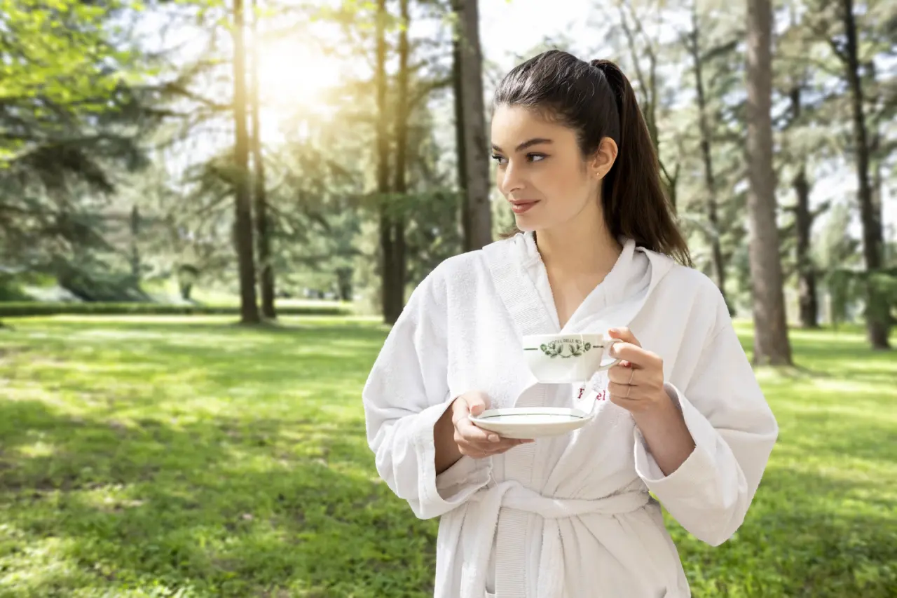 Terme di Monticelli in Monticelli Terme – Frau im Bademantel mit Tee im Hotelpark | Wellnesshotel Emilia-Romagna