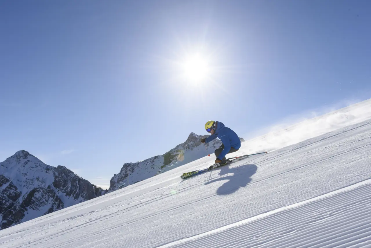 Dynamischer Skifahrer auf sonniger Piste mit Bergpanorama, ideal für Winterurlaub im Hotel Via Salina.