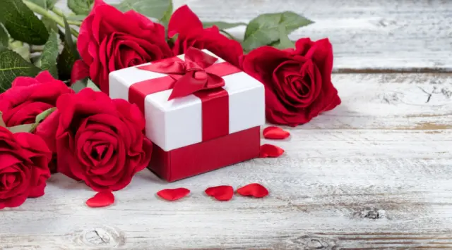 Romantische Dekoration mit roten Rosen und Geschenkbox auf Holztisch im Hotel Via Salina.