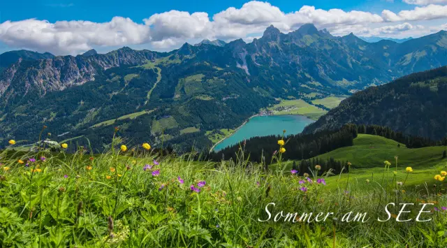 Malerische Berglandschaft mit türkisblauem See und blühenden Wiesen im Sommer, nahe Hotel Via Salina.
