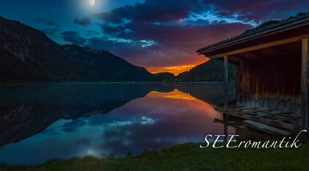 Romantischer Sonnenuntergang über dem See mit Bergen und Bootshaus in der Nähe des Hotel Via Salina.