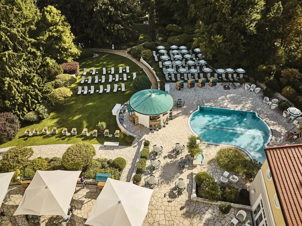 Luftaufnahme des weitläufigen Hotelgartens mit Pool, Sonnenterrassen und Strandkörben im Travel Charme Strandidyll Heringsdorf.