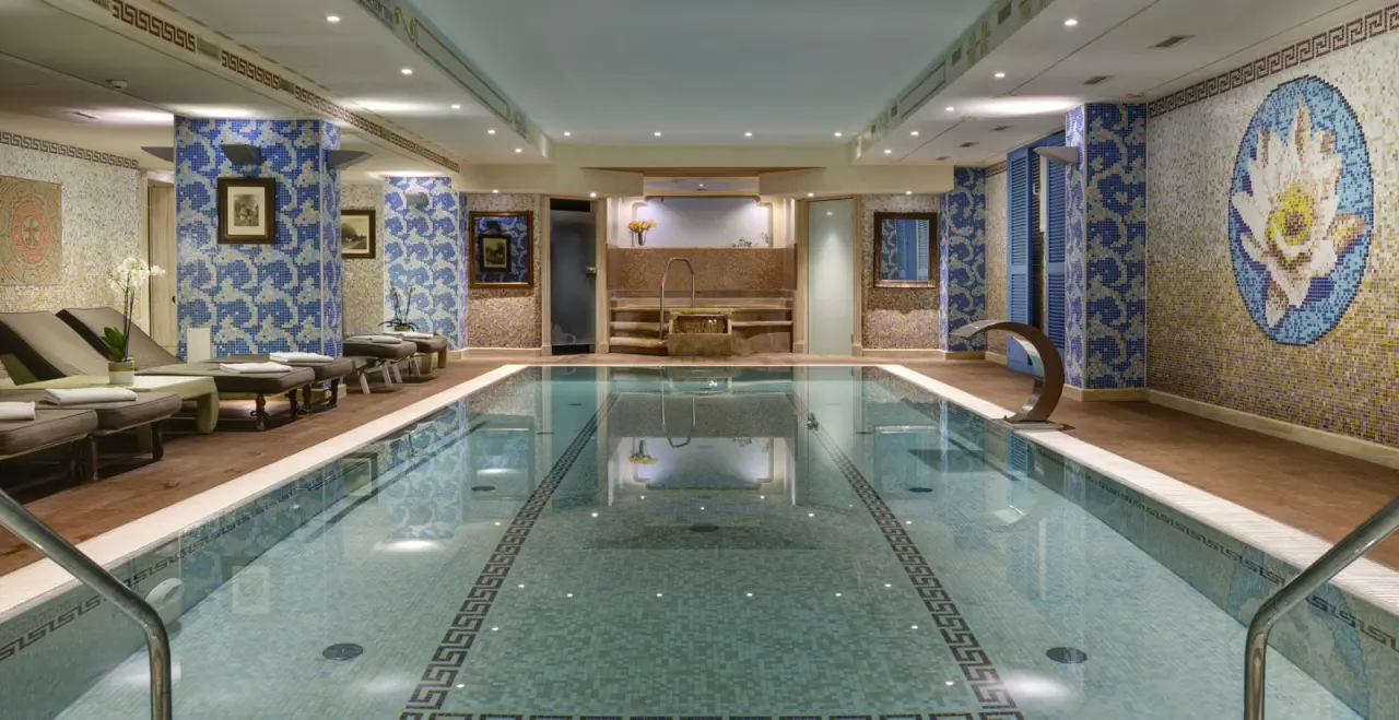 Grosszügiger Innenpool mit Mosaikfliesen und Liegeflächen im Wellnessbereich des Swiss Diamond Hotel.
