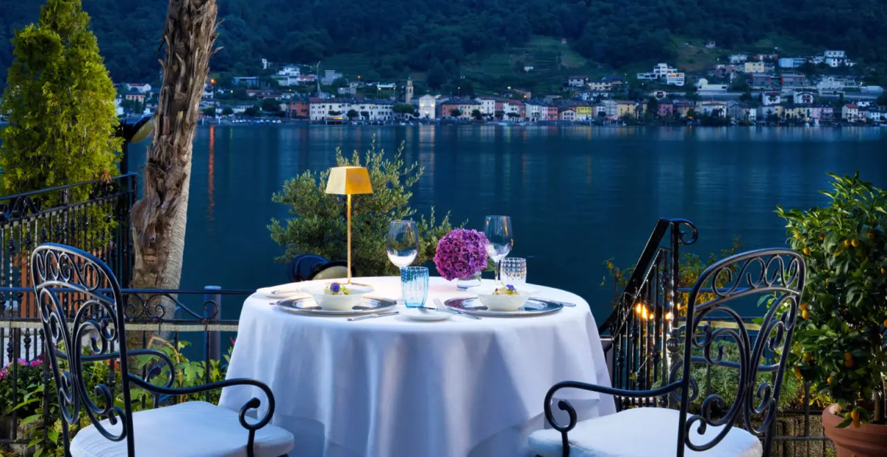 Romantisches Abendessen auf der Terrasse des Swiss Diamond Hotel mit Blick auf den Luganersee und beleuchtetes Dorf.