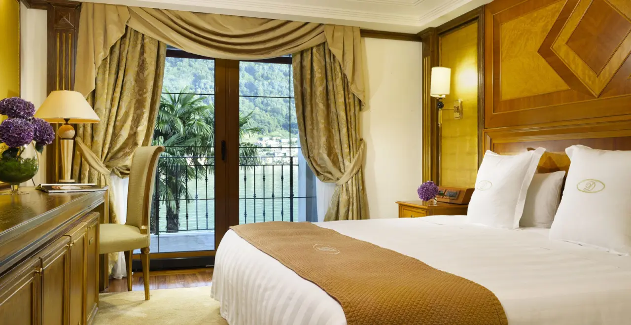 Luxuriöses Hotelzimmer im Swiss Diamond Hotel mit Doppelbett, eleganten Möbeln und Balkonblick auf den See und Berge.