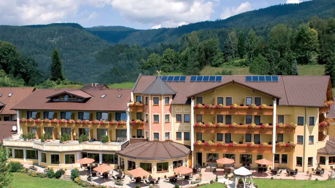 Aussenansicht des Kristall & Vitalhotel Bergknappenhof mit blühenden Balkonen und Bergkulisse.