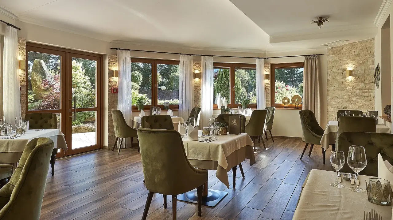 Einladendes Restaurant im Kristall & Vitalhotel Bergknappenhof mit Blick in den grünen Garten und gemütlichen Sitzbereichen.
