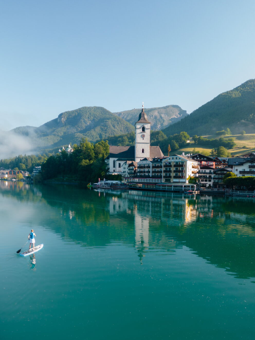 Romantik Hotel Im Weissen Rössl in St.Wolfgang – Sommeransicht des Wolfgangsees mit Paddleboarder | Wellnesshotel Salzkammergut