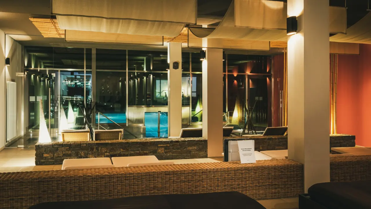Einladender Ruhebereich mit bequemen Liegen und Blick auf den beleuchteten Pool im Wellnessbereich des Hotel Lauterbad.
